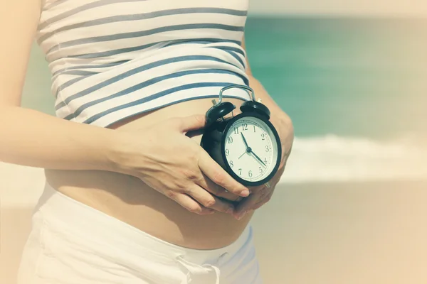 Mujer embarazada sosteniendo alarma-reloj — Foto de Stock