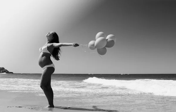 Young pregnant woman holding red balloons — Stock Photo, Image