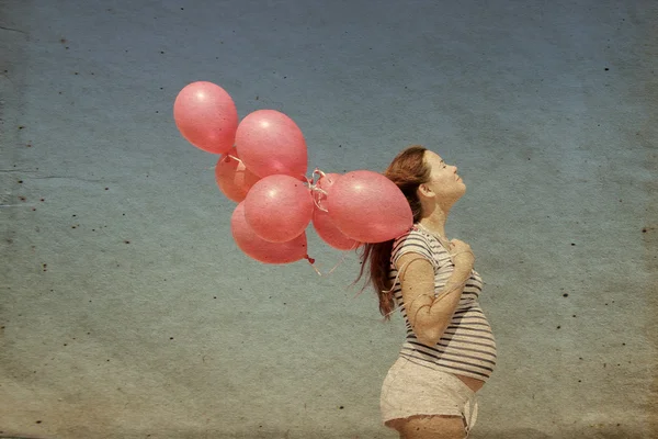 Young pregnant woman holding red balloons — Stock Photo, Image