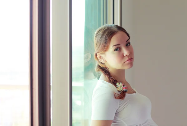 Mooie vrouw staat voor het venster — Stockfoto