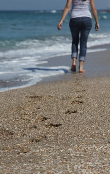 Giovane donna che cammina sulla spiaggia. Concentrati sulla sabbia . — Foto Stock