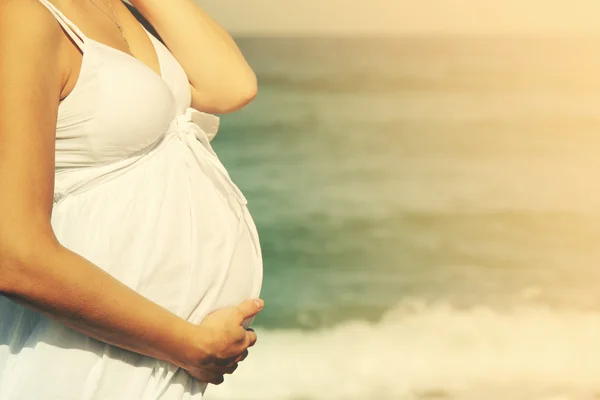 Vacker gravid kvinna som står på stranden — Stockfoto