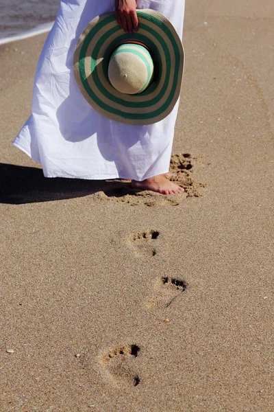 Giovane donna in abito bianco a piedi in spiaggia — Foto Stock