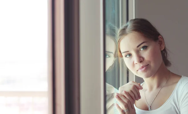 Mooie vrouw staat voor het venster — Stockfoto