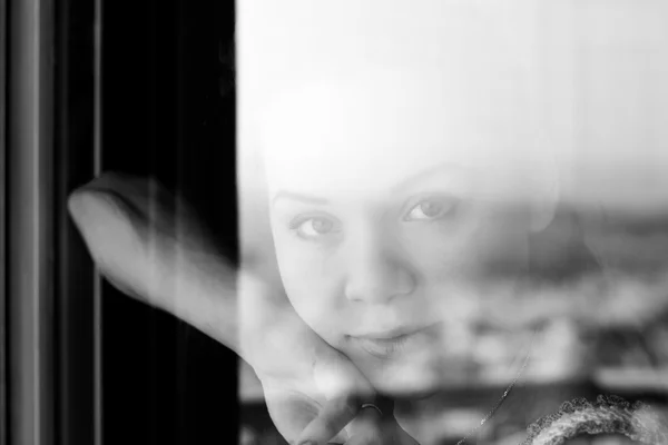 Woman looking through a window — Stock Photo, Image