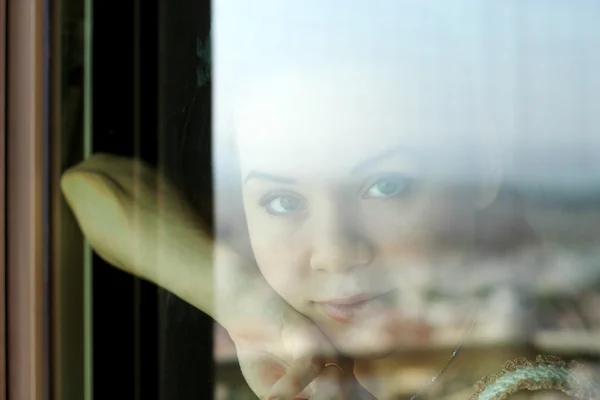 Woman looking through a window — Stock Photo, Image