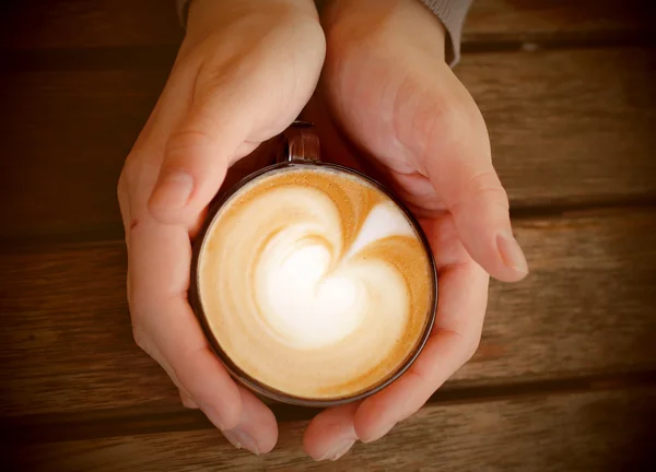 Woman hands with cappuccino on a wood table — Stock Photo, Image