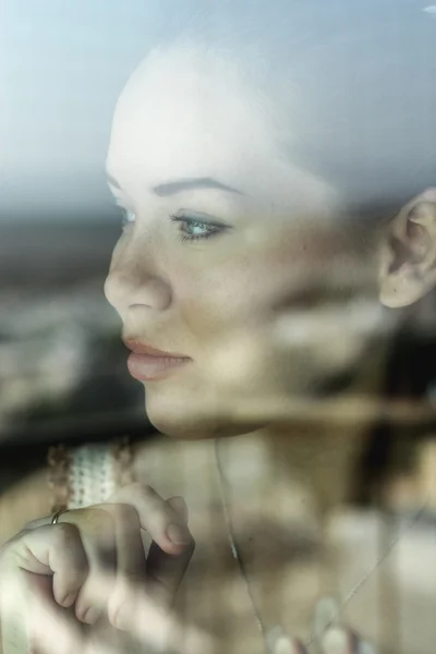 Woman looking through a window — Stock Photo, Image