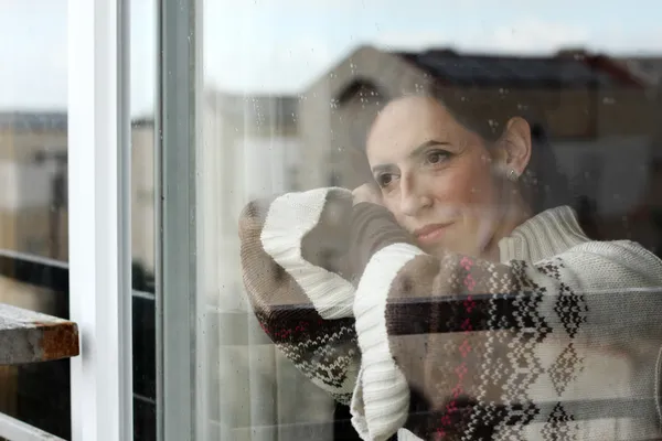 Грустная девушка смотрит в окно — стоковое фото