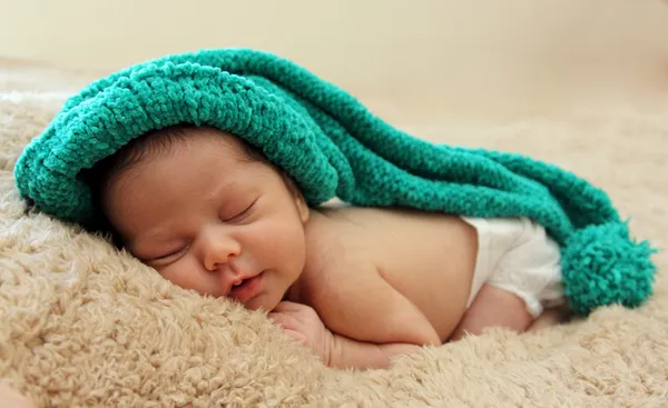 Bebé recién nacido está usando un sombrero azul y acostado durmiendo — Foto de Stock