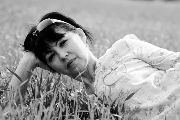 Starsza kobieta, leżąc na trawie — Zdjęcie stockowe