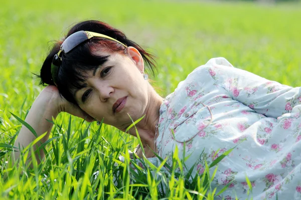 Reife Frau liegt im Gras — Stockfoto