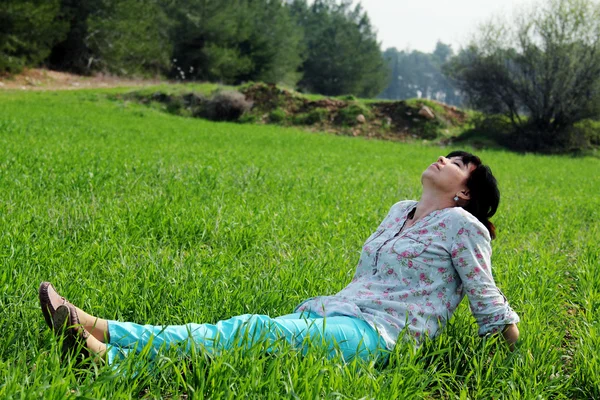 Reife Frau sitzt im Gras — Stockfoto
