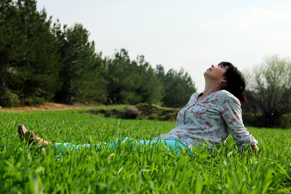 Reife Frau sitzt im Gras — Stockfoto