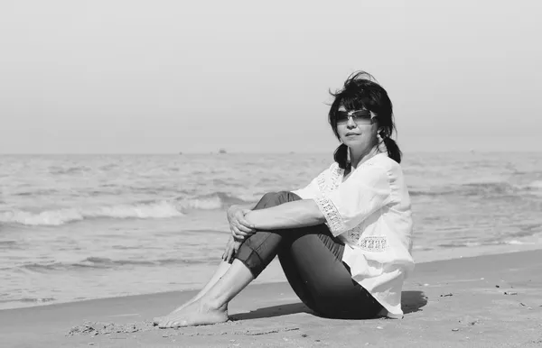 Vrouw zit op het strand — Stockfoto