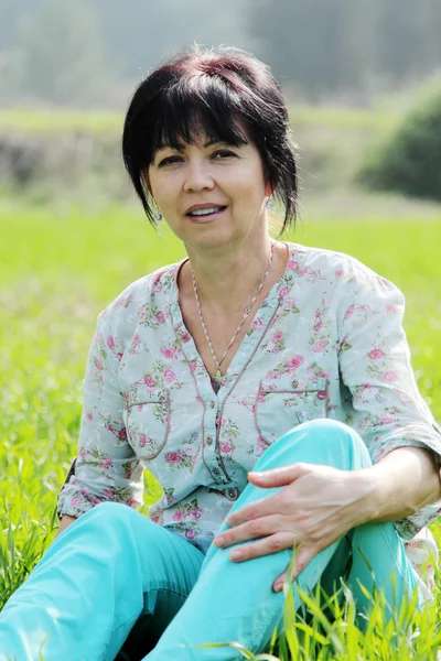 Vrouw zitten in gras — Stockfoto