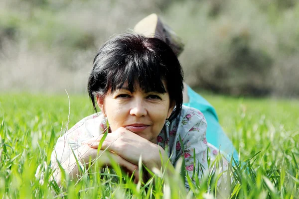 Mature woman lying in grass — Stock Photo, Image