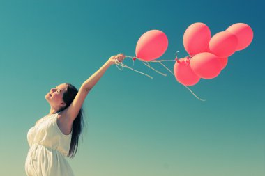 genç bir kadın tutarak kırmızı balonlar