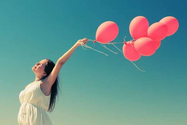 Young woman holding red balloons — Stock Photo, Image