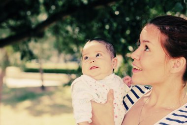 Mutlu anne ve bebeğinin açık havada portresi.