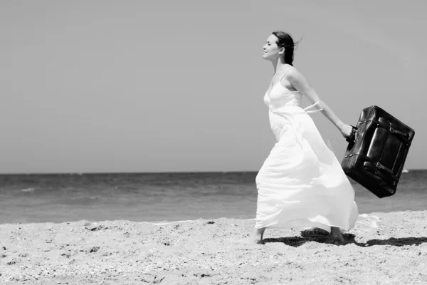 Žena s kufrem na pláži — Stock fotografie
