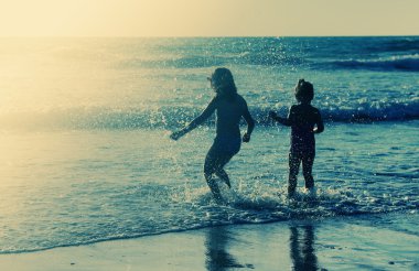 gün batımında sahilde oynarken iki mutlu çocuk