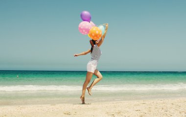 mujer con globos de colores en la playa