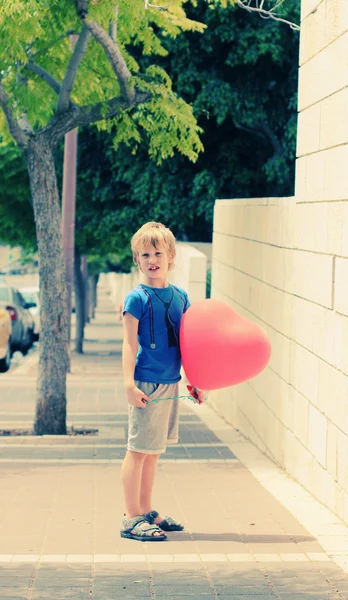 可爱的 6 岁男孩举行红气球 — 图库照片
