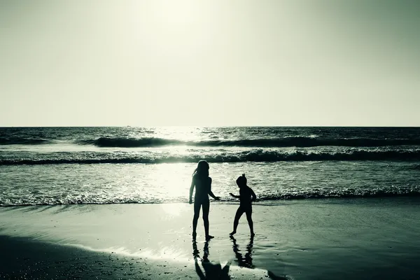 Twee gelukkige jonge geitjes spelen op het strand bij zonsondergang — Stockfoto