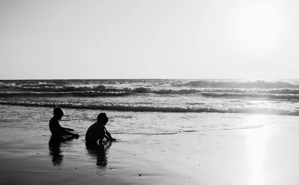 Twee gelukkige jonge geitjes spelen op het strand — Stockfoto