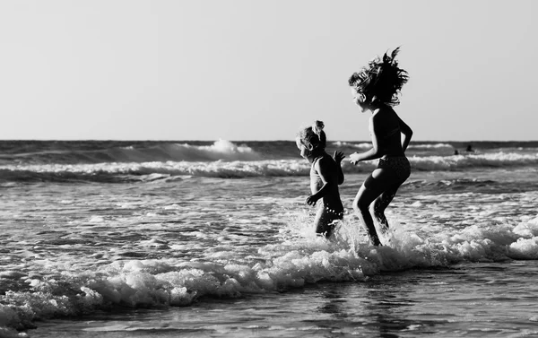 Dos niños felices jugando en la playa al atardecer —  Fotos de Stock