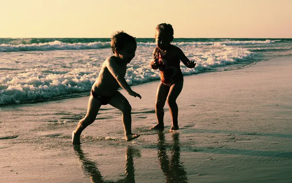 Twee gelukkige jonge geitjes spelen op het strand — Stockfoto