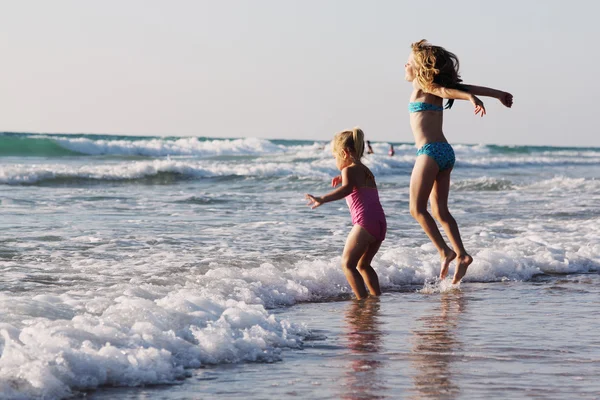 Deux enfants heureux jouant sur la plage au coucher du soleil — Photo