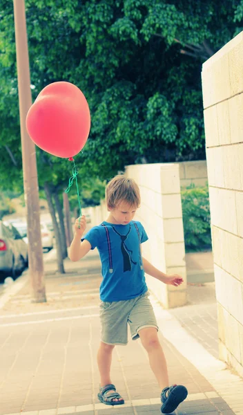 Cute 6 years old boy holding red balloon — Stock Photo, Image