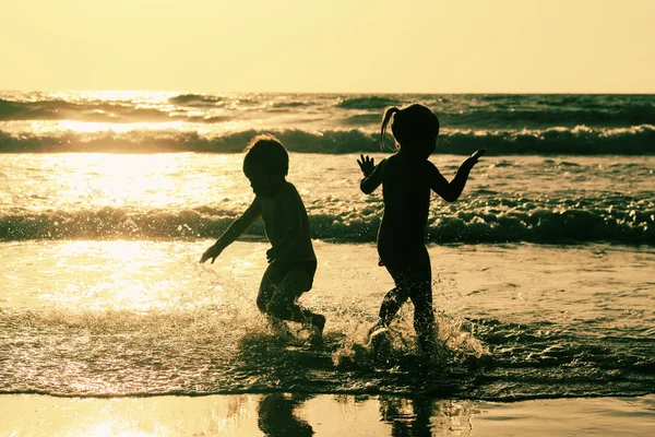 Zwei glückliche Kinder spielen am Strand — Stockfoto