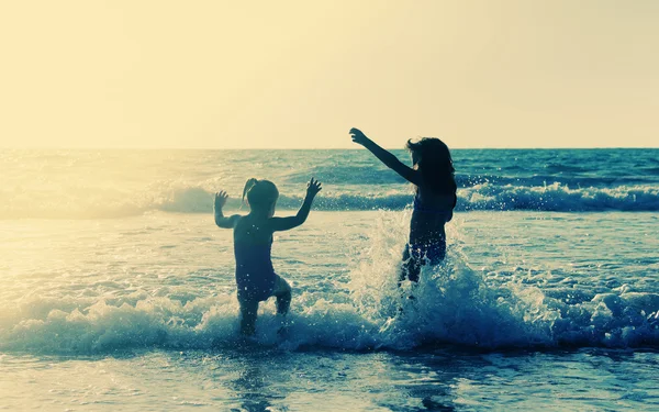 Due bambini felici che giocano sulla spiaggia al tramonto — Foto Stock