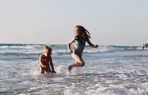 Zwei glückliche Kinder spielen am Strand bei Sonnenuntergang — Stockfoto