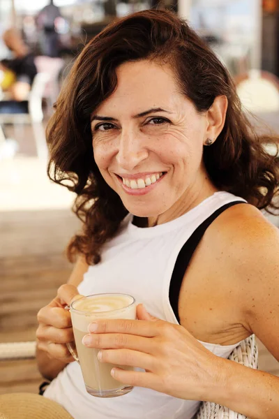 Kadın sahildeki yazlık kafede oturuyor.