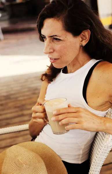 Kadın sahildeki yazlık kafede oturuyor.