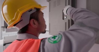 Elektrikçiler elektrik kabini kontrolündeki kontrol panelini denetleyerek elektrik şalterini değiştiriyorlar..