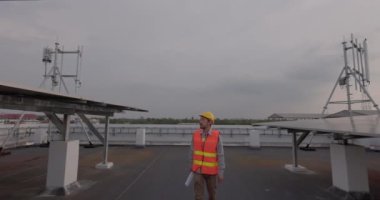 Asyalı mühendisler bir enerji santralinde ve çatılarda güneş panellerini inceliyor.