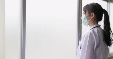 Hastanenin iş yerinde pencerenin önünde poz veren neşeli kızıl saçlı bir kadın doktorun görüntüsü..