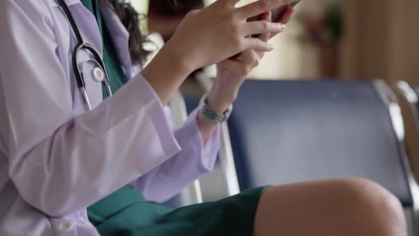 Młoda Lekarka Korzystająca Telefonu Podczas Siedzenia Krześle — Wideo stockowe