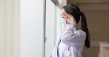 Kadın doktor, hastanenin penceresinin yanında endişeli bir şekilde bekliyor..