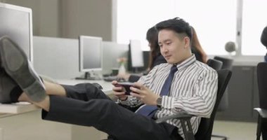 Bir bilgisayarla masa başında çalışmak eğlenceli bir iş anlayışı olan genç adam ofisteki çalışanlar akıllı telefon oyunları oynamaya bağımlıdır..