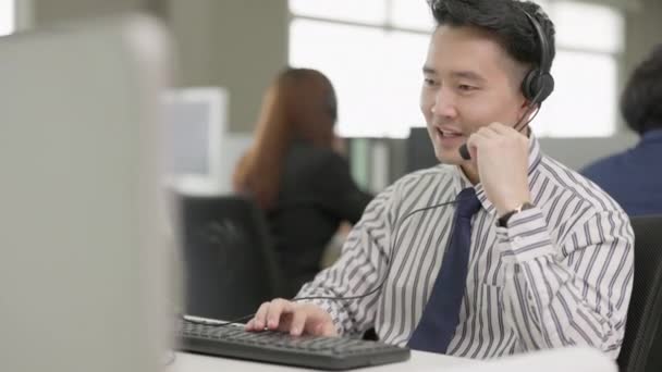 亚洲男子电话营销运营商头戴耳机 与呼叫中心城市办公室的团队合作 — 图库视频影像