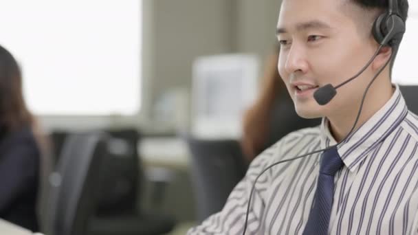 亚洲男子电话营销运营商头戴耳机 与呼叫中心城市办公室的团队合作 — 图库视频影像