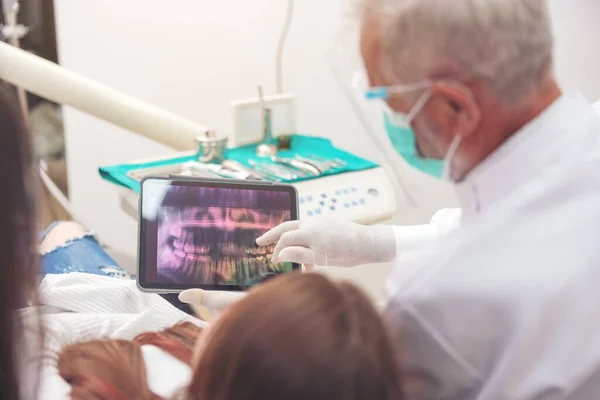在会诊过程中 牙医和病人一边讨论治疗方案 一边用牙齿X光检查数字平板屏幕 三维断层扫描技术 — 图库照片