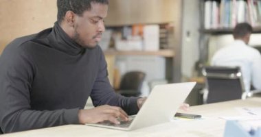 Tatmin olmuş bir Afro-Amerikalı işadamı dizüstü bilgisayarında çalışırken gülümsüyor. Ofiste Başarılı Girişimci Araştırma Yapıyor ve Notebook Slow Motion Video 'da Yazıyor