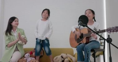 Hoş bir aile oturma odasında eğleniyor, gitar çalıyor ve evlerinin rahatlığından birlikte şarkı söylüyorlar..